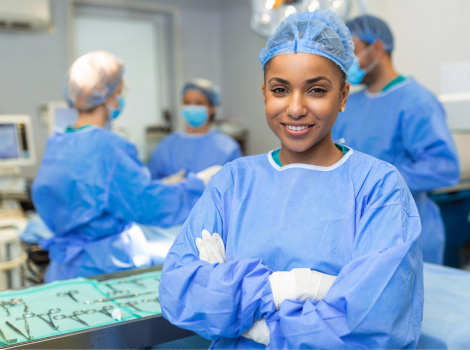 Young, female surgical tech in an operating room smiles with arms crossed