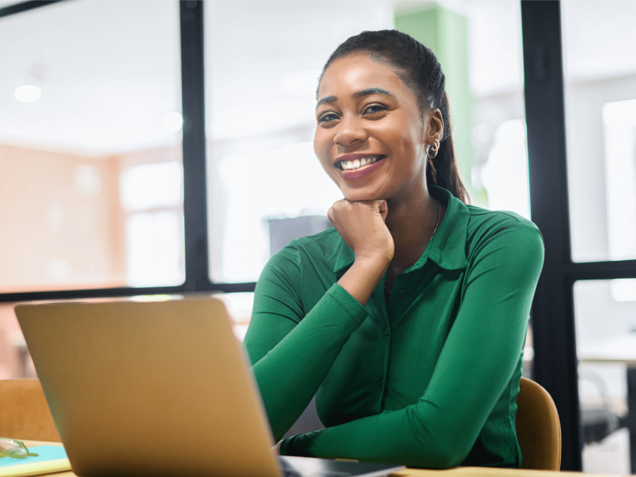 Woman smiling and sitting behind a laptop