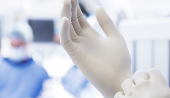 Close up on the hands of a medical professional putting on surgical gloves
