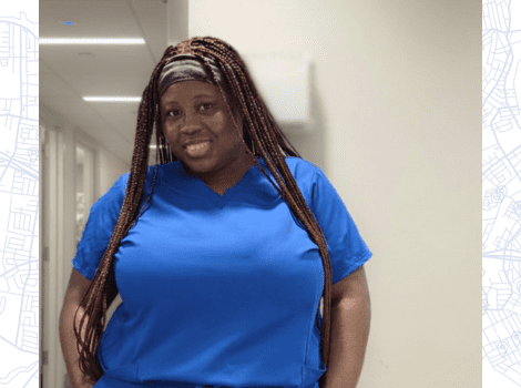 Rafiatou, in the hospital, dressed in blue scrubs, smiling at the camera