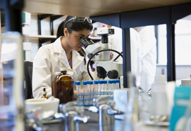 A researcher in a lab looking through a microscope
