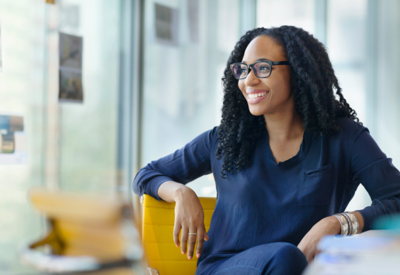 A young woman with classes sitting at a table smiling
