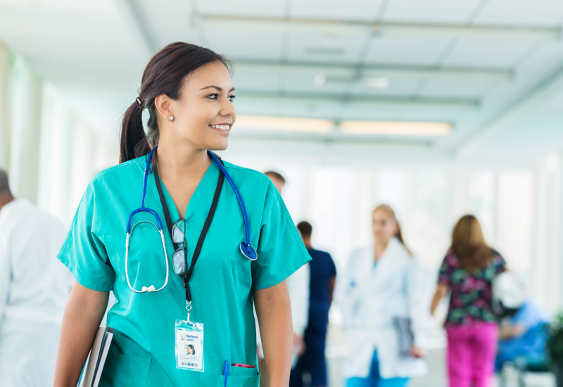A nursing student in turquoise scrubs with a stethoscope and lanyard
