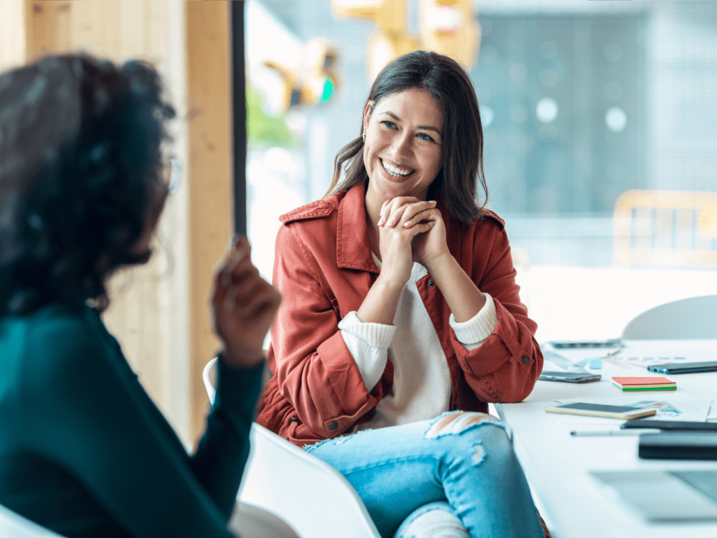 Two women in office having a friendly discussion.