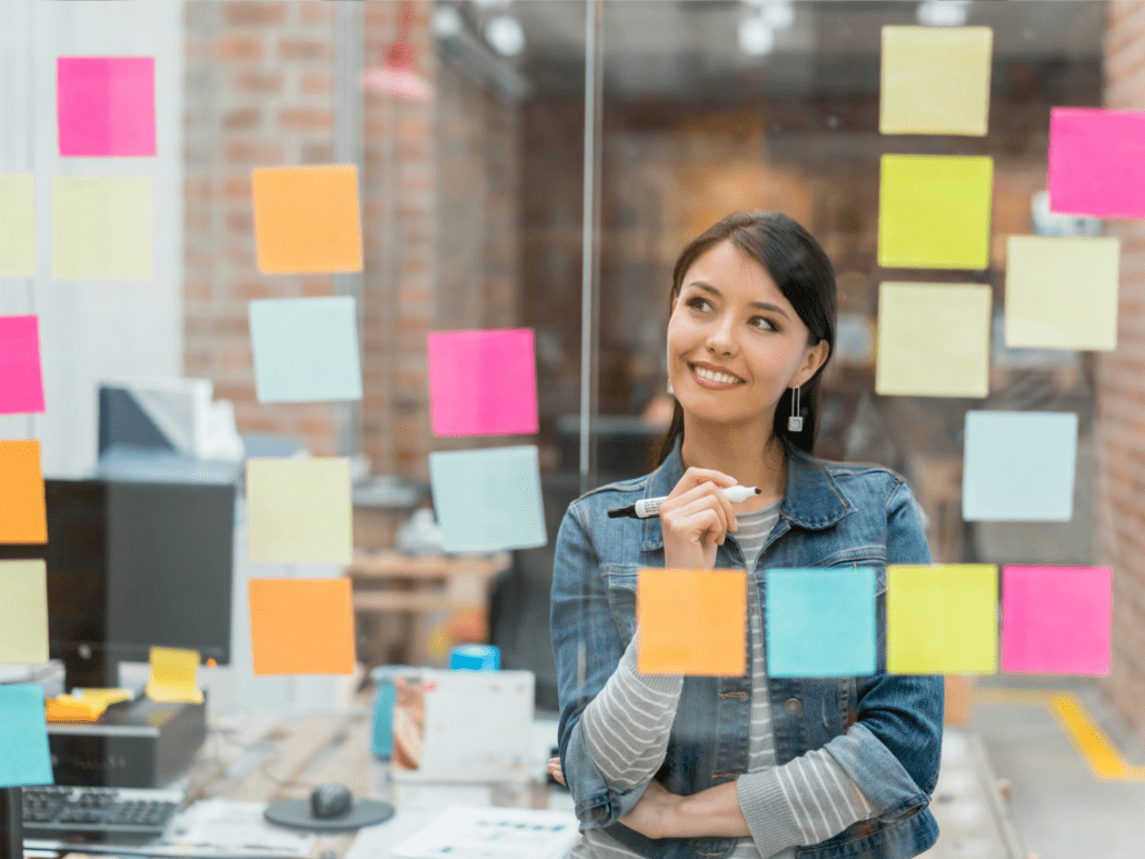 Woman working on white board with notes
